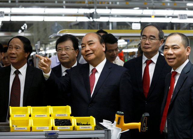팜녓브엉(오른쪽 첫번째) 빈그룹 회장이 이달 14일(현지시간) 빈패스트 하이퐁 공장에서 응우옌쑤언푹(가운데) 베트남 총리를 안내하고 있다. /하이퐁=로이터연합뉴스