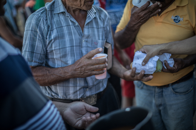지난해 2월 17일(현지시간) 한 베네수엘라 이주민이 브라질 호라이마주 시몬 볼리바르 광장에서 식량을 제공받기 위해 줄을 서 있다. /호라이마=블룸버그