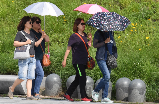 대구의 최고기온이 32℃까지 오르는 등 무더운 날씨를 보인 지난 20일 오후 서울 강북구 북서울꿈의숲에서 시민들이 양산으로 내리쬐는 햇빛을 가린 채 산책하고 있다./오승현기자