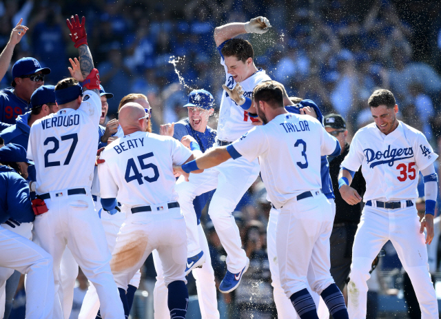 다저스 윌 스미스(가운데)가 24일 메이저리그 콜로라도전에서 9회 끝내기 스리런을 터뜨린 뒤 홈을 밟으며 동료들의 축하를 받고 있다. /로스앤젤레스=AFP연합뉴스