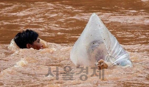베트남 디엔비엔성에서 한 남성이 아이가 담긴 비닐봉지를 손에 쥔 채 강을 헤엄쳐 건너고 있다. /연합뉴스