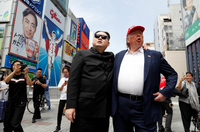 김정은 북한 국무위원장으로 분장한 하워드 X(왼쪽)와 도널드 트럼프 미국 대통령으로 분한 데니스 앨런이 26일 주요 20개국(G20) 정상회의 개최가 예정된 오사카의 한 거리에서 퍼포먼스를 벌이고 있다./오사카=로이터연합뉴스