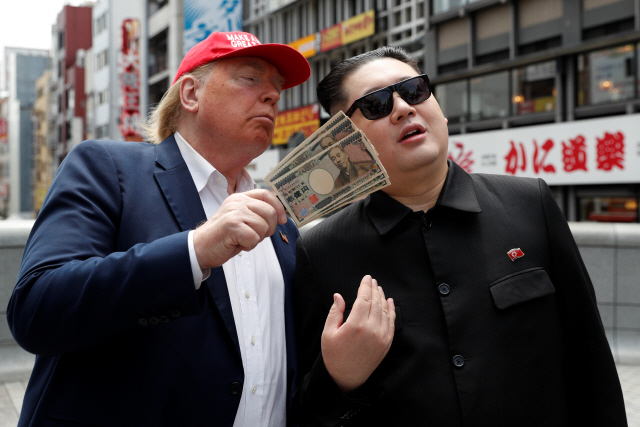 김정은 북한 국무위원장으로 분장한 하워드 X(오른쪽)와 도널드 트럼프 미국 대통령으로 분한 데니스 앨런이 26일 주요 20개국(G20) 정상회의 개최가 예정된 오사카의 한 거리에서 퍼포먼스를 벌이고 있다./오사카=로이터연합뉴스