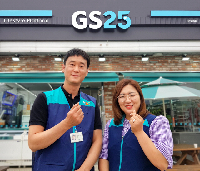 GS25 경영주(오른쪽)와 담당 영업직원이 점포 앞에서 손가락으로 하트를 그려보이고 있다./사진제공=GS25