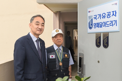 왕정홍 방사청장이 27일 오후 경기도 과천시의 참전유공자 윤용황씨의 집을 방뭄, ‘국가 유공자의 집 명패’를 달아주고 있다./방사청 제공