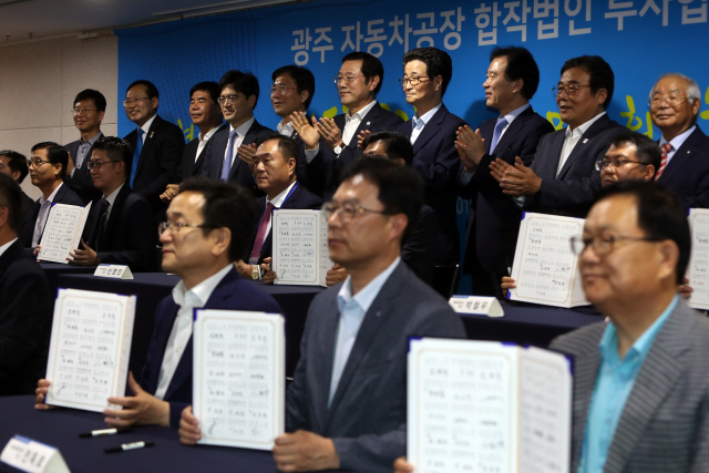 성윤모(뒷줄 왼쪽 다섯번째) 산업통상자원부 장관과 이용섭(〃 〃여섯번째) 광주시장이 28일 광주시청에서 열린 ‘광주형 일자리 자동차공장 합작법인 투자협약식’에 참석해 32개 참여사 대표들과 함께 박수를 치고 있다./광주=연합뉴스