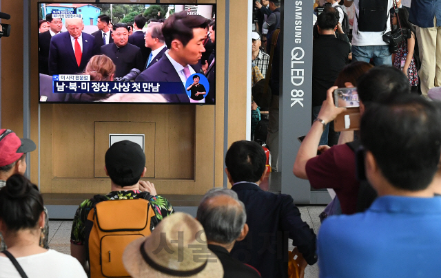 30일 오후 서울역에서 시민들이 문재인 대통령과 도널드 트럼프 미국 대통령, 김정은 북한 국무위원장이 군사분계선에서 만나는 역사적인 순간을 TV를 통해 시청하고 있다./오승현기자 2019.6.30