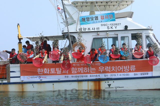 한화토탈 임직원과 지역주민들이 충남 서산 삼길포 앞바다에서 우럭치어와 바지락 종패 방류 행사를 갖고 있다. 사진제공=한화토탈