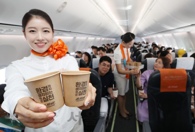 제주항공 승무원들이 5일 김포공항에서 출발해 제주로 향하는 비행기 안에서 친환경 종이빨대와 친환경 펄프 소재 종이컵을 사용하는 플라스틱 줄이기 캠페인을 하고 있다./이호재기자