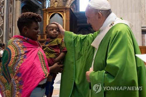 프란치스코 교황이 8일 바티칸 성베드로 대성당에서 난민과 이민자를 위한 미사를 집전한 뒤 이민자 가정의 아이를 쓰다듬고 있다./AFP=연합뉴스