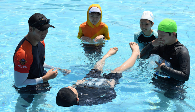 해양경찰이 지난 4일 서울 여의도 야외수영장에서 학생들에게 페트병을 활용한 생존수영법을 가르치고 있다./오승현기자