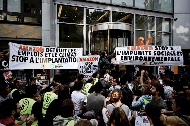 프랑스 시민단체가 지난 2일(현지시간) 파리 근교 클리시의 아마존 프랑스법인 본부 건물 앞에서 ‘아마존이 일자리를 해친다’ 등의 내용이 담긴 팻말을 들고 시위를 벌이고 있다. /클리시=AFP연합뉴스
