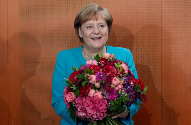 앙겔라 메르켈 독일 총리가 17일(현지시간) 베를린에서 열린 내각회의에서 생일축하 꽃다발을 받고 환하게 웃고 있다. /베를린=로이터연합뉴스