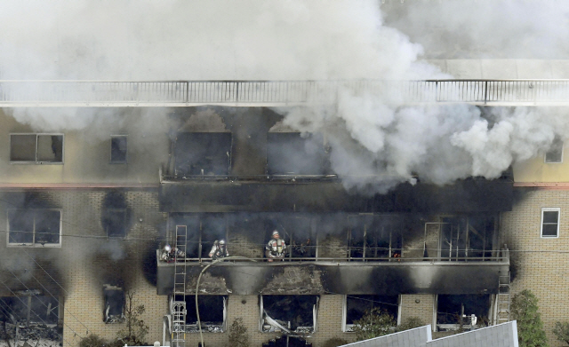 18일(현지시간) 방화로 추정되는 화재가 발생해 연기가 치솟고 있는 일본 교토의 유명 애니메이션 제작회사 ‘교토 애니메이션’ 건물에서 소방대원들이 진화작업을 벌이고 있다. /교토=AP연합뉴스