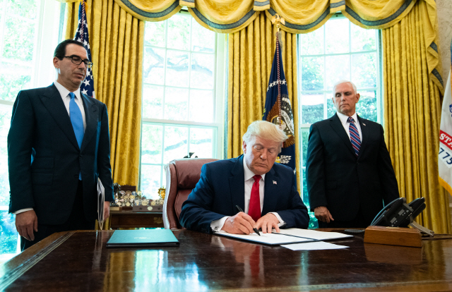 도널드 트럼프(가운데) 미국 대통령이 지난달 24일(현지시간) 백악관 집무실에서 스티븐 므누신(왼쪽) 재무장관과 마이크 펜스 부통령이 지켜보는 가운데 이란에 대한 추가 제재를 단행하는 내용의 행정명령에 서명하고 있다. /워싱턴DC=블룸버그