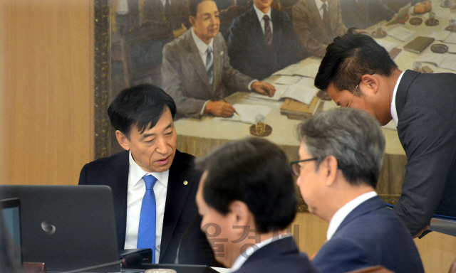 이주열(왼쪽) 한국은행 총재가 18일 서울 한은 본관에서 열린 금융통화위원회 회의에 앞서 직원의 보고를 받고 있다.  /이호재기자