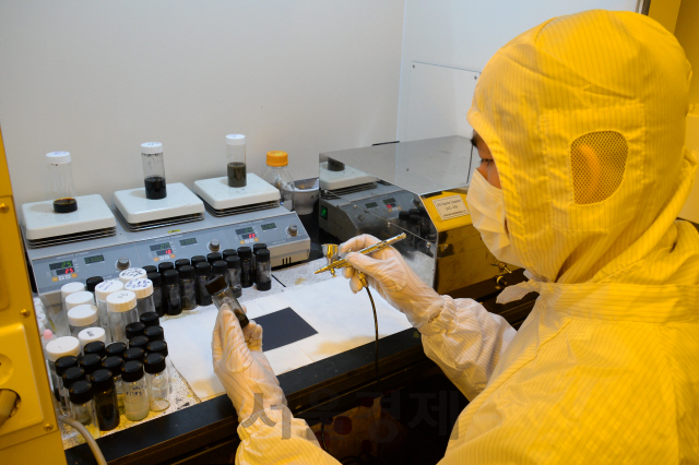 ETRI의 한 연구원이 전도성 나노 소재를 유연 플라스틱 기판 위에 뿌리며 코팅하고 있다. /ETRI