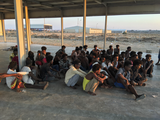 25일(현지시간) 선박 전복 사고에서 구조된 난민들이 리비아 트리폴리에서 동쪽으로 100km 가량 떨어진 해안가에 앉아있다. /트리폴리=AP연합뉴스