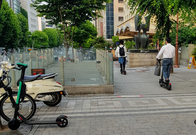 서울 강남에서 인도에 주차돼있는 전동킥보드 옆으로 이용자들이 전동킥보드를 타고 인도를 달리고 있다. /권경원기자