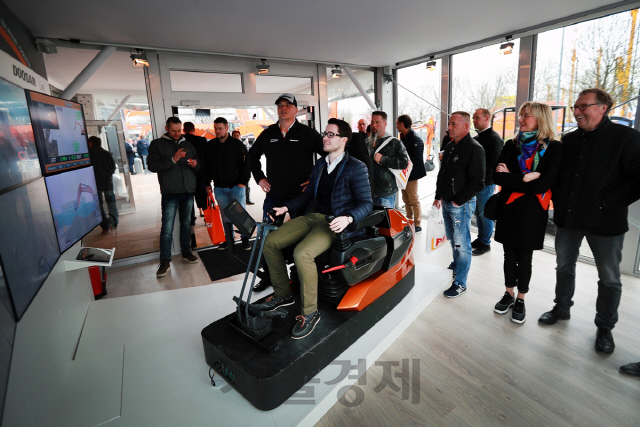 두산인프라코어가 독일 ‘바우마(Bauma) 2019’에 참가해 독일 뮌헨 전시장에서 8,500km 떨어진 인천의 굴삭기를 조종하는 5G 원격제어 기술을 시연하고 있다./사진제공=두산인프라코어