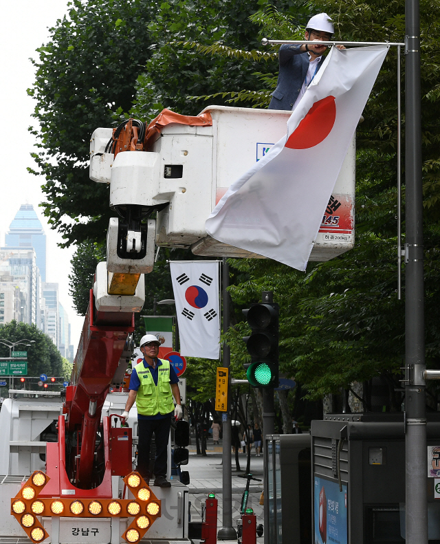 2일 오후 서울 강남구 테헤란로에서 구청 관계자들이 일본의 화이트리스트 한국 제외조치에 대한 항의 표시로 거리에 게양된 만국기 중 일장기를 하기하고 있다. 강남구는 테헤란로와 영동대로, 압구정로데오거리에 게양된 일장기 14기를 모두 하기하고 일본의 수출규제조치 철회 시까지 자리를 비워둘 방침이다./오승현기자 2019.8.2