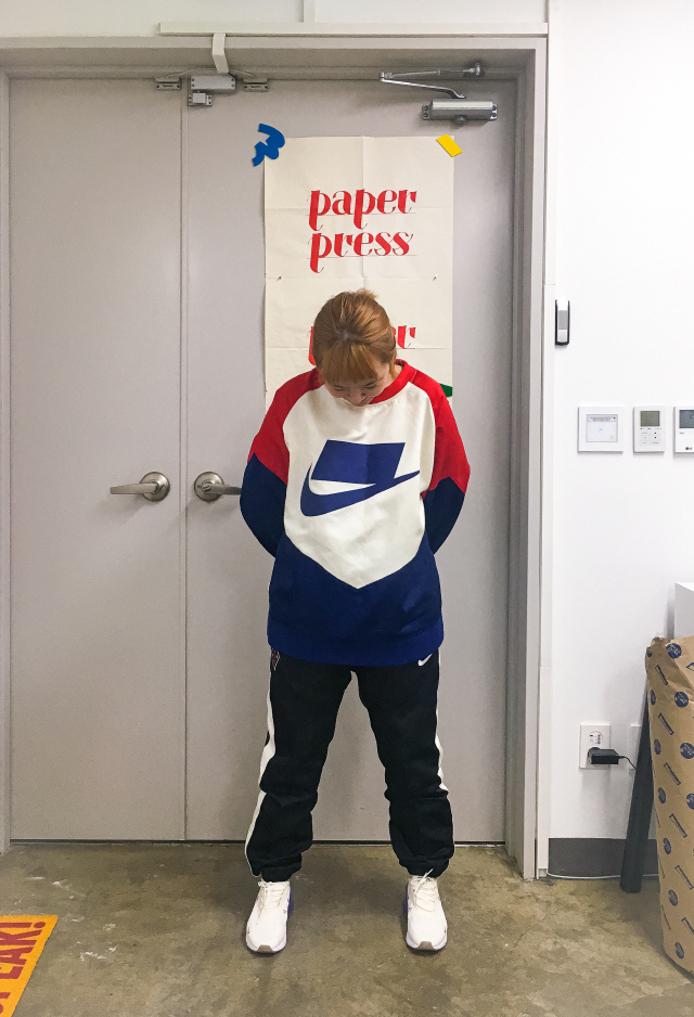 ‘나이키’ 트레이닝복을 입고 작업실 문 앞에서 포즈를 취하고 있는 박신우 디자이너