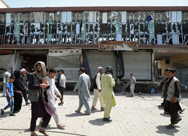 아프가니스탄 수도 카불의 경찰 검문소 인근에서 7일(현지시간) 발생한 차량폭탄 테러로 유리창 등이 부서진 건물 앞을 시민들이 지나고 있다. /카불=로이터연합뉴스