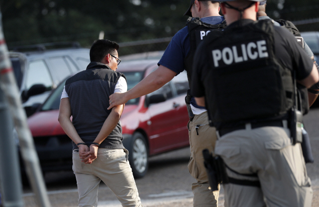 7일(현지시간) 미국 미시시피주 모튼에 있는 한 식품공장에서 경찰들이 불법 이민 노동자를 체포해 연행하고 있다. /모튼=AP연합뉴스