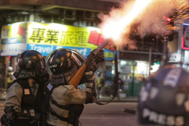 지난 11일(현지시간) 홍콩 완차이에서 경찰들이 시위대를 향해 최루탄을 발사하고 있다.   /홍콩=AFP연합뉴스