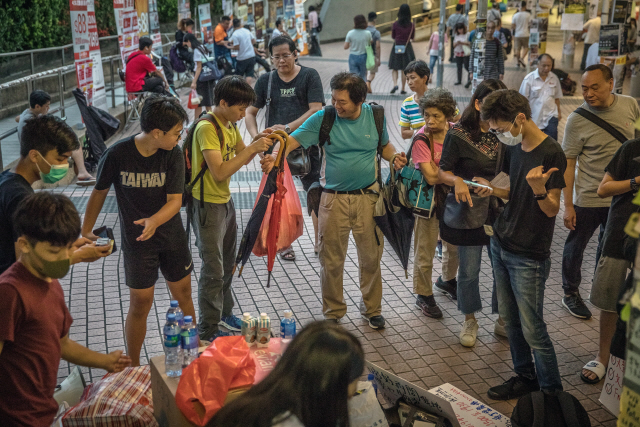 19일(현지시간) 한 남성이 홍콩 록푸의 MTR역 근처에서 송환법 반대 시위대에게 우산과 생수 등을 나눠주고 있다. /홍콩=EPA연합뉴스