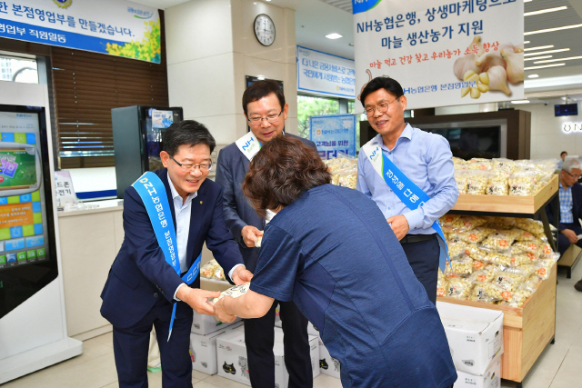 20일 서울 중구 본점영업부에서 유윤대(왼쪽) NH농협은행 부행장이 임직원들과 고객들에게 마늘을 나눠주고 있다./사진제공=농협은행