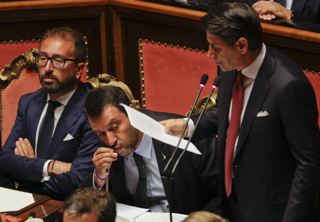 주세페 콘테(오른쪽) 이탈리아 총리가 20일(현지시간) 사임에 앞서 로마 상원 의사당에서 정국 관련 연설을 하는 가운데 마테오 살비니(가운데) 부총리 겸 내무장관이 묵주에 입을 맞추고 있다.       　 /로마=AP연합뉴스