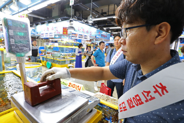 지난 21일 오전 서울 송파구 가락시장에서 민관합동 점검단 관계자가 명절을 앞두고 매장에서 사용하는 저울을 학인하고 있다./연합뉴스