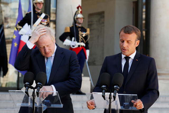 보리스 존슨(왼쪽) 영국 총리가 22일(현지시간) 프랑스 파리 엘리제궁에서 에마뉘엘 마크롱 대통령과 공동성명을 발표하며 머리를 감싸고 있다. /파리=로이터연합뉴스