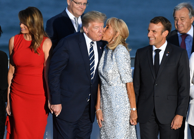 도널드 트럼프 미국 대통령이 25일 프랑스 비아리츠에서 열린 G7 정상회의 후 기념 촬영에서 주최국인 프랑스의 영부인인 브리지트 마크롱 여사와 볼 키스를 하고 있다./사진 = 현지 공동취재단