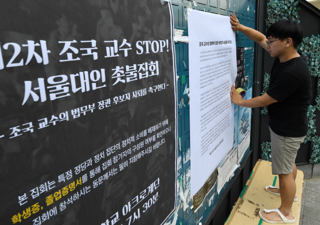 서울대 총학생회 관계자가 26일 서울대 학생회관 게시판에 조국 법무부 장관 후보자의 사퇴를 촉구하는 대자보를 붙이고 있다. /성형주기자