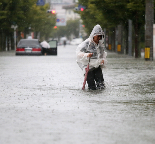 28일 일본 규수지방의 사가현에서 한 시민이 이날 쏟아진 폭우로 무릎까지 물이 차오른 도로를 건너고 있다. /사가=EPA연합뉴스