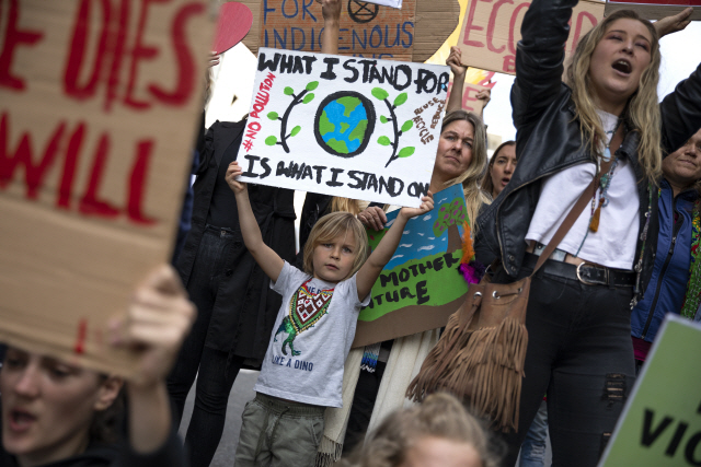 27일(현지시간) 남아프리카공화국 케이프타운의 브라질영사관 앞에서 기후변화 방지 운동단체 ‘멸종저항’ 소속 환경운동가들이 아마존 열대우림 지키기 시위를 벌이는 가운데 한 아이가 지구를 보호하자는 내용의 피켓을 들고 있다.      /케이프타운=EPA연합뉴스
