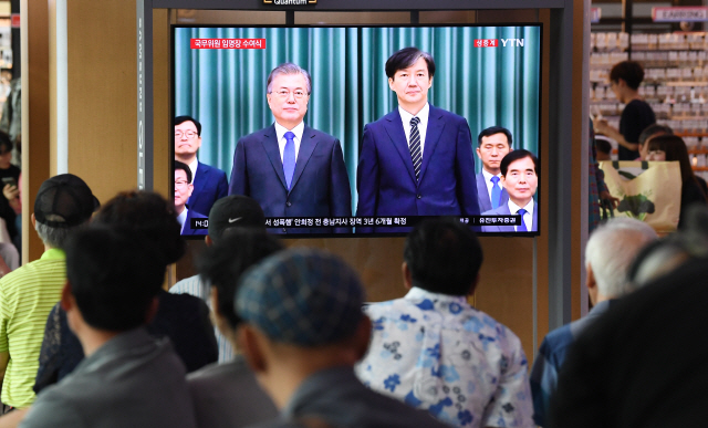 9일 서울 용산구 서울역 대합실에서 시민들이 조국 법무부 장관 임명장 수여식 후 문재인 대통령과 조 장관이 기념촬영하는 모습을 TV로 지켜보고 있다.      /오승현기자