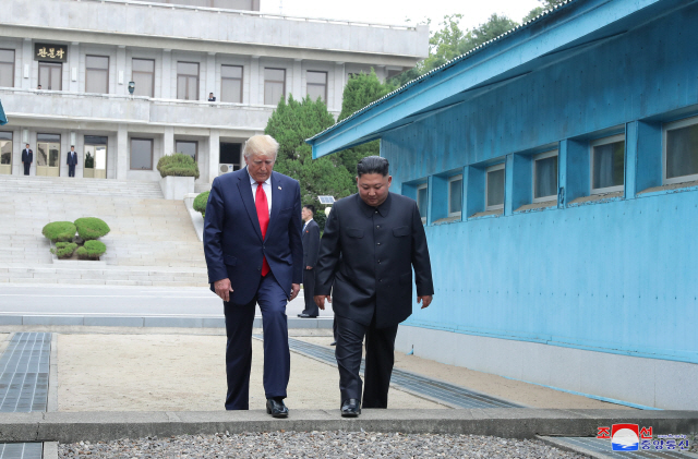 도널드 트럼프 미국 대통령과 김정은 북한 국무위원장이 6월 30일 오후 판문점에서 군사분계선을 넘고 있다./조선 중앙통신=연합뉴스