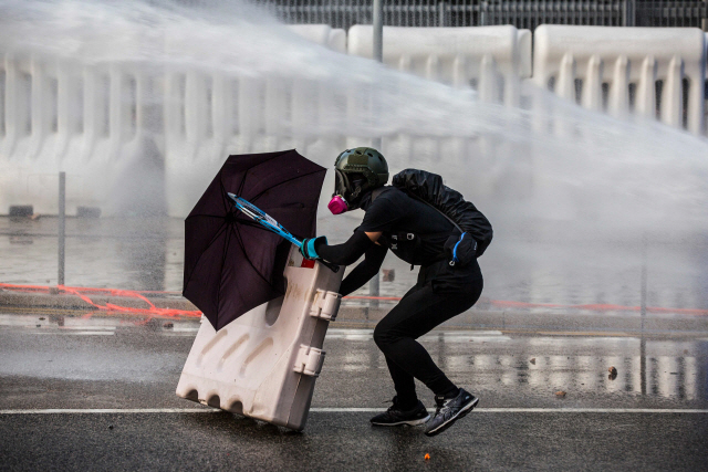 지난 15일 홍콩 민주화 시위자가 경찰의 물대포에 맞서 우산을 펼쳐들고 있다.   /AFP연합뉴스