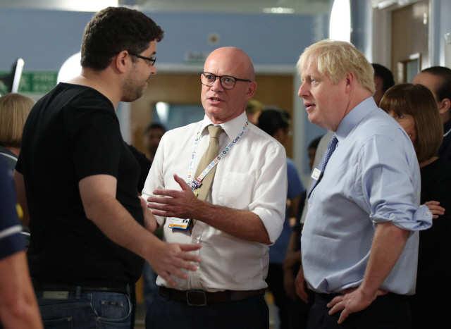 보리스 존슨(오른쪽) 영국 총리가 18일(현지시간) 런던 북동부에 위치한 윕스 크로스 대학병원에서 국민보건서비스에 대해 항의하는 한 환자 보호자의 말을 듣고 있다. /런던=AFP연합뉴스