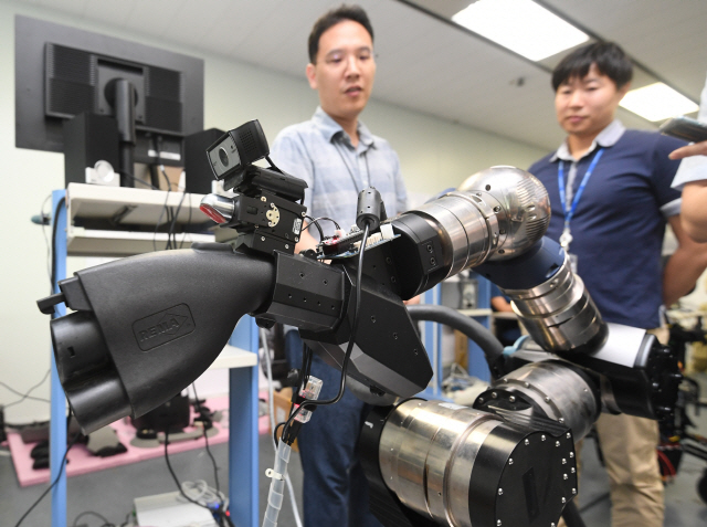 현대차 로보틱스팀 연구진이 전기차 충전용 로봇팔을 시연해보이고 있다./의왕=권욱기자