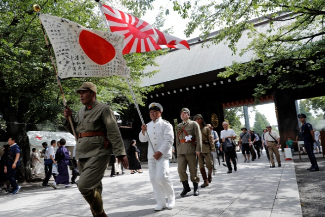 일본의 패전 기념일인 지난 8월 15일 제국주의 군복을 입은 일본인들이 욱일기를 들고 도쿄 야스쿠니신사로 입장하고 있다./로이터연합뉴스