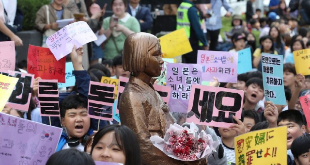 25일 오후 서울 종로구 중학동 옛 일본대사관 앞 소녀상에서 열린 제1406차 일본군성노예제 문제 해결을 위한 정기 수요시위에 참석한 학생들이 손수 만든 팻말을 들어보이고 있다./연합뉴스