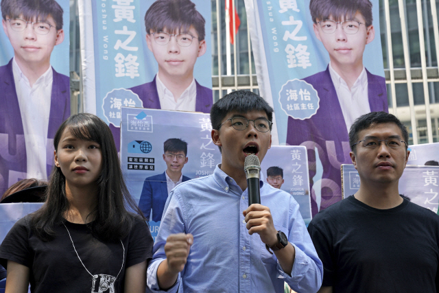 홍콩 ‘우산혁명’의 주역인 조슈아 웡(가운데) 데모시스토당 비서장이 28일(현지시간) 홍콩 정부청사 앞에서 지방선거 출마를 선언하고 있다.   /홍콩=AP연합뉴스