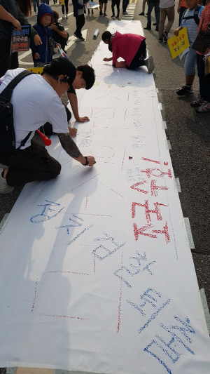 시민들이 5일 서울 서초역 사거리 일대에서 열린 ‘검찰개혁 촉구 촛불문화제’ 참가에 앞서 도로에 설치된 종이 위에 조국 법무부 장관을 지지하는 글귀를 적고 있다.