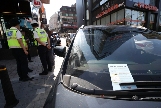 불법 주정차 행위 특별 단속에 나선 서울시 교통지도과 단속반원들이 8일 서울 강남구 도산대로 일대 인도에서 적발된 차량 소유주와 대화를 나누고 있다. 서울시는 경찰청·자치구와 함께 지난 1일부터 강남 지역 6차로 이상 대로변에 위치한 대형 음식점들의 주차대행을 통한 불법 주정차를 집중 단속하고 있다. /연합뉴스