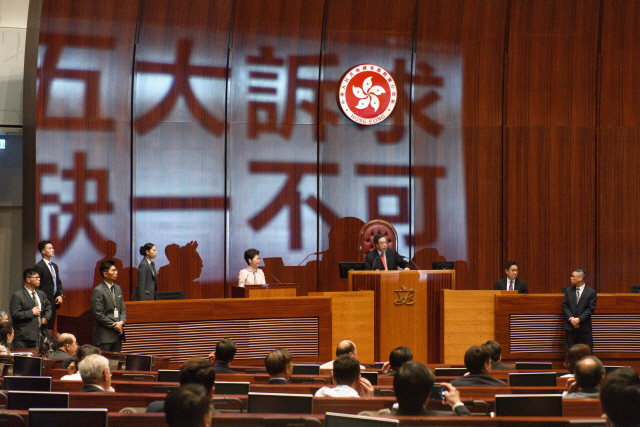 홍콩 의회인 입법회에서 16일(현지시간) 캐리 람 행정장관의 시정연설 도중 야당 의원들이 빔프로젝터를 이용해 연단에 ‘5대 요구 사항, 하나도 빼놓을 수 없다’는 문구를 비추고 있다.    /홍콩=EPA연합뉴스