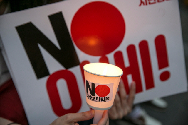 지난 8월 3일(현지시간) 서울에서 열린 아베 신조 일본 총리 규탄 집회에서 한 시민이 ‘No 아베(노 아베)’ 라고 쓰인 팻말과 촛불을 들고 있다. /서울=블룸버그